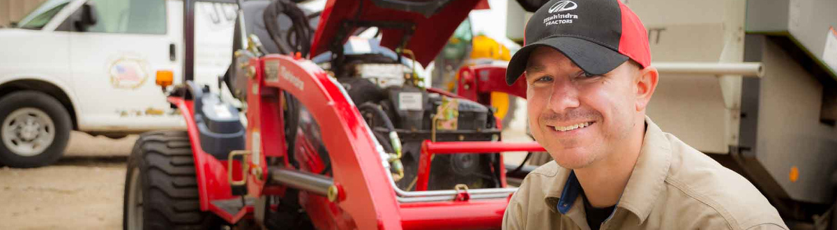 Man smiling in front of a red tractor.